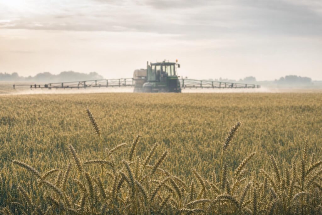 Agricultural field with crop sprayer in the distance